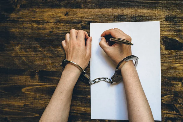 Женщина в наручниках, подписывает признание, вид сверху — стоковое фото