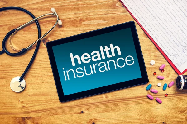 Health insurance title on tablet computer placed on doctors desk — Stock Photo, Image