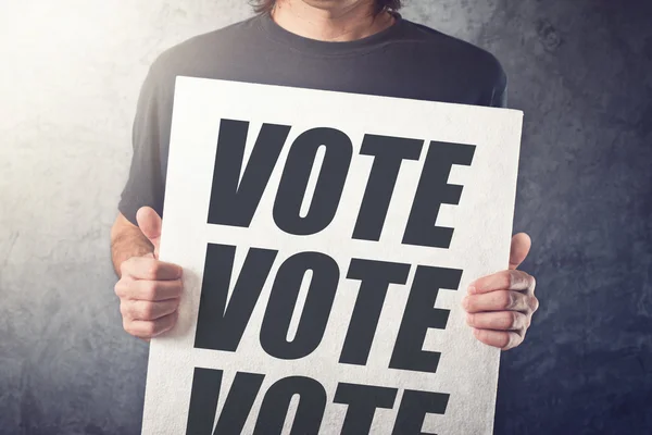 Homem segurando cartaz com rótulo de voto — Fotografia de Stock