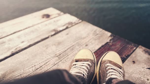 Man with crossed legs relaxing on riverbank pier — Stock Video