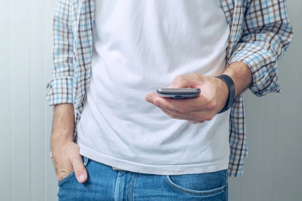 Περιστασιακή άνθρωπος σε λευκό t-shirt που χρησιμοποιούν κινητό τηλέφωνο — Φωτογραφία Αρχείου