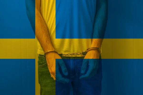 Arrested man with cuffed hands wearing shirt with Swedish flag — Stock Photo, Image