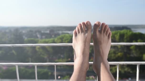 Hombre descalzo relajándose en vacaciones junto al mar en el balcón — Vídeo de stock