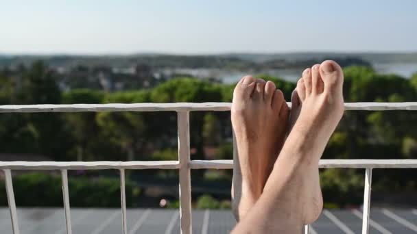 Hombre descalzo relajándose en vacaciones junto al mar en el balcón — Vídeos de Stock