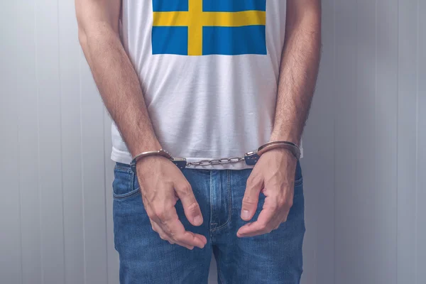 Арестованный мужчина с наручниками в рубашке со шведским флагом — стоковое фото