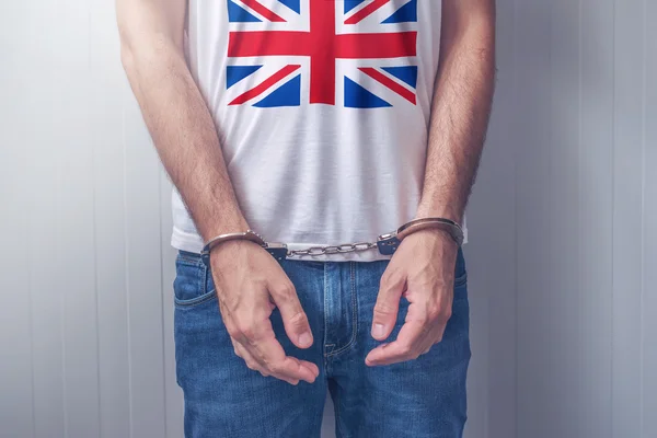 Arrested man with cuffed hands wearing shirt with UK flag — Stock Photo, Image