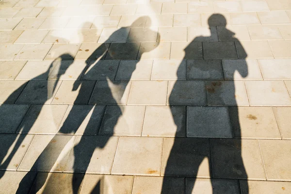 Des gens projetant des ombres sur le trottoir — Photo