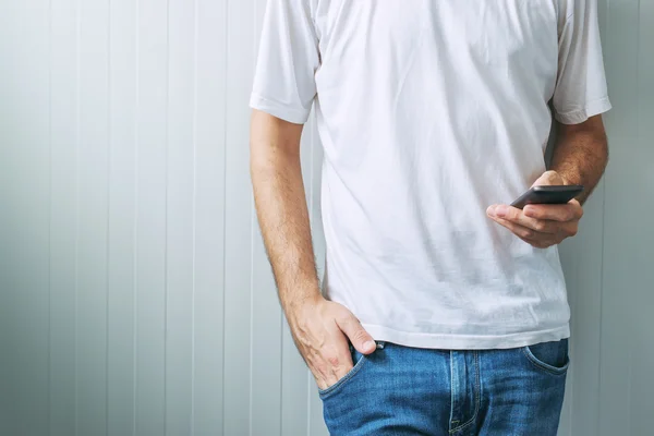 Casual homem de t-shirt branca usando telefone celular — Fotografia de Stock
