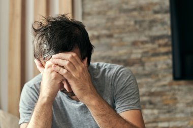Bunalımlı somurtkan adam oturma odasında tek başına oturuyor ve düşünüyor, yetişkin beyaz erkek orta yaş krizine giriyor.