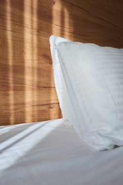 Beyaz yastık yatak odasında, yatak odasında. Sabah güneşi perdelerin arasından parlıyor.