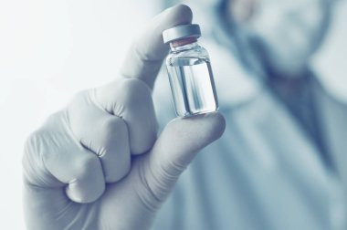 Coronavirus aşısı konsepti için aşı şişesi tutan tıp doktoru, seçici odaklanma