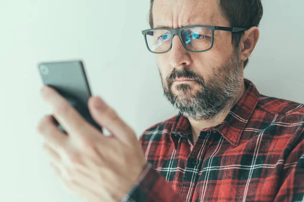 Porträtt Mellanvuxen Man Med Glasögon Och Flanellskjorta Med Mobiltelefon Inomhus — Stockfoto