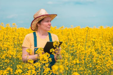 Tecavüz tarlasında yenilikçi teknoloji tableti kullanan kadın tarımcı. Seçici odak noktası.