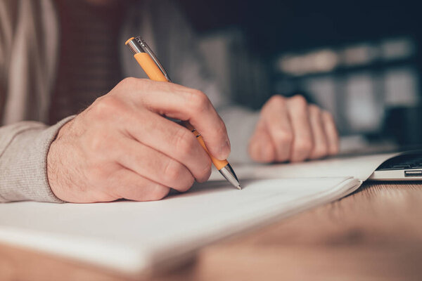 Фрилансер, пишущий список на рабочем столе дома, закрывается выборочно