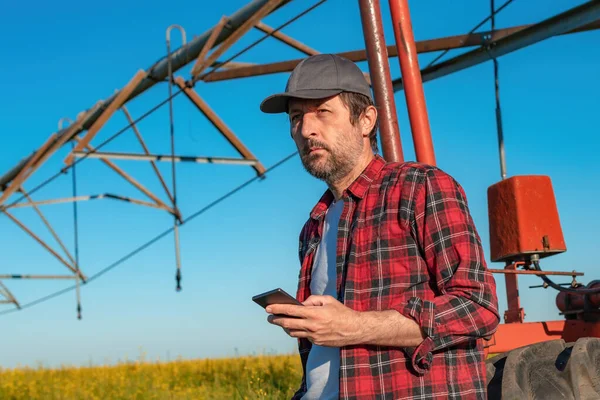 Çiftçi Merkez Pivot Sulama Ekipmanının Yanında Cep Telefonu Kullanıyor Kolza — Stok fotoğraf