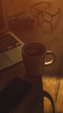 Morning coffee in dark home office interior, low key image with selective focus