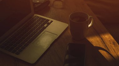 Morning coffee in dark home office interior, low key image with selective focus