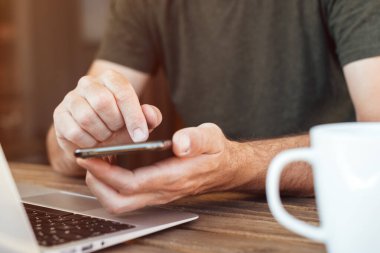 Serbest çalışan sabah balkonda cep telefonu kullanıyor, ev kavramı üzerine çalışıyor, seçici odaklanma