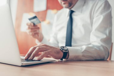 İşadamı dizüstü bilgisayar ve kredi kartı kullanarak e-bankacılık işlemini tamamlıyor.