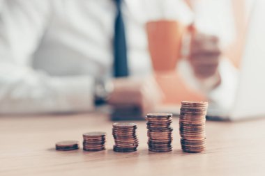 Tatmin olmuş iş adamı kahve içerken önünde bozuk para yığını, seçici bir odak ile kapat.