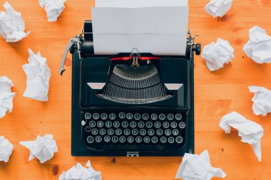 Writer's block concept, top view of vintage typewriter machine and crumpled paper on wooden desk
