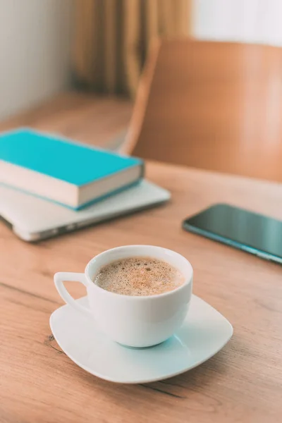 フリーランスの仕事のためのカフェインとコーヒーの重要性 コーヒーカップ 携帯電話 ノートパソコン 家庭用オフィステーブルの本 — ストック写真