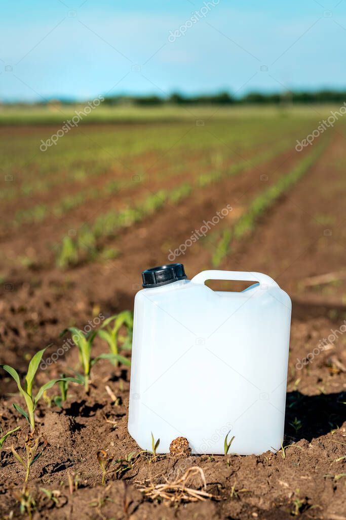 Herbicide plastic canister can in corn field, crop protection concept