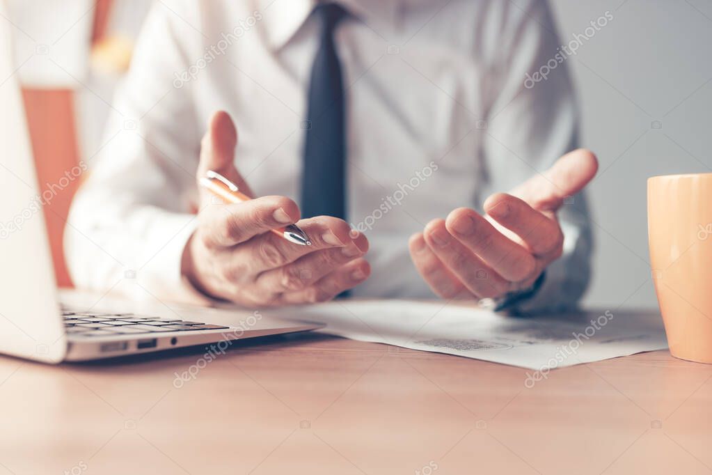 Businessman explaining, closeup of hands with pencil at office desk, man talking and gesticulating, selective focus