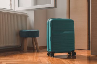 Seyahat çantası otel odasının açık kapısının arkasında, seçici bir odak noktası.