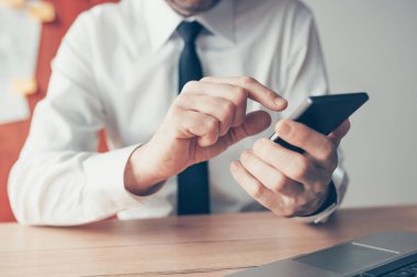 Ofis masasında cep telefonu kullanan iş adamı, seçici odaklanma