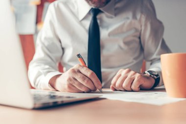 Ofis masasına notlar yazan işadamı, seçici odaklanma ile kapat