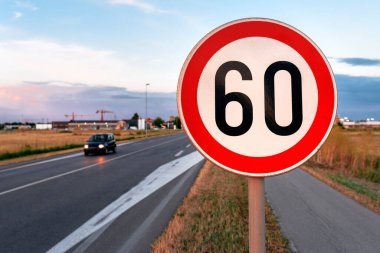 Yol kenarındaki 60 km / h hız sınırı, arka planda hareket eden bulanık araba