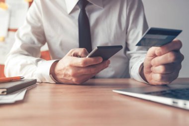 Cep telefonu bankacılığı, iş adamı çevrimiçi finansal işlemler için akıllı telefon ve kredi kartı kullanıyor, seçici odaklı kapat