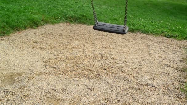 Empty swing seat swaying at playground in the park. — Stock Video