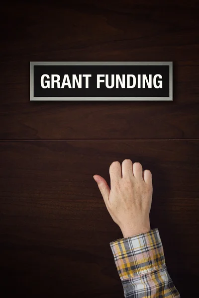 A mão está batendo na porta de financiamento Grant — Fotografia de Stock