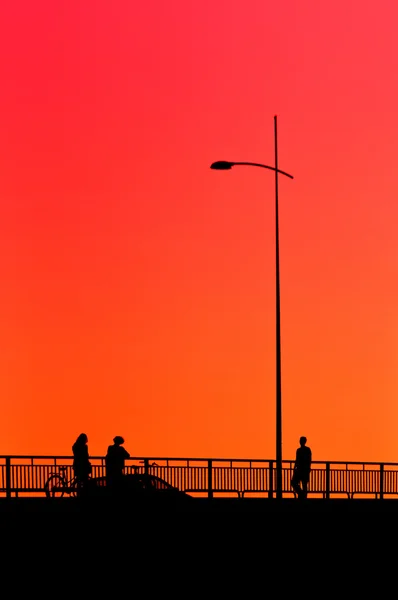 Menschen auf der Brücke im Sonnenuntergang — Stockfoto