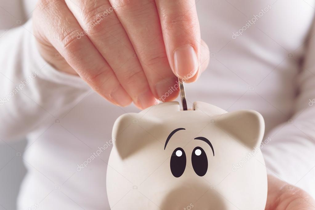Woman putting coin in piggy coin bank