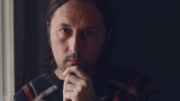Erwachsener kaukasischer Mann steht am Fenster seines Wohnzimmers und denkt — Stockvideo