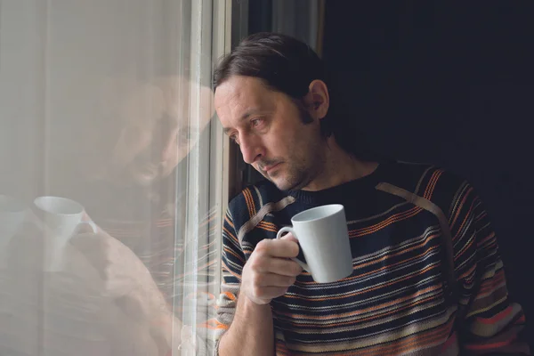 Triste hombre junto a la ventana bebiendo café — Foto de Stock