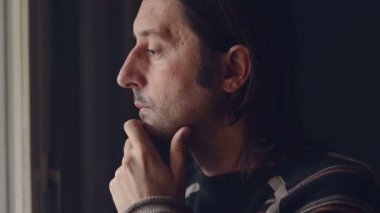 Yetişkin beyaz erkek ayakta pencerenin onun oturma odası ve düşünme