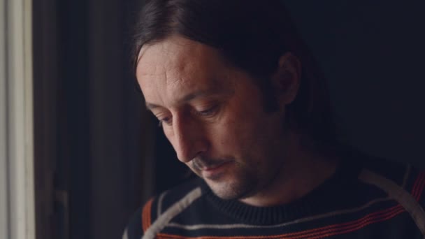 Ενηλίκων καυκάσιος λυπημένος άνθρωπος στέκεται από το παράθυρο του καθιστικού και κλάμα σε απόγνωση — Αρχείο Βίντεο