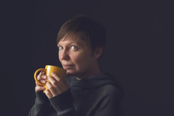 Bella donna che beve tè e caffè in camera oscura — Foto Stock