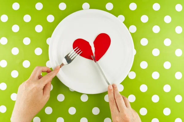 Mujer comiendo corazón roto en un plato blanco — Foto de Stock