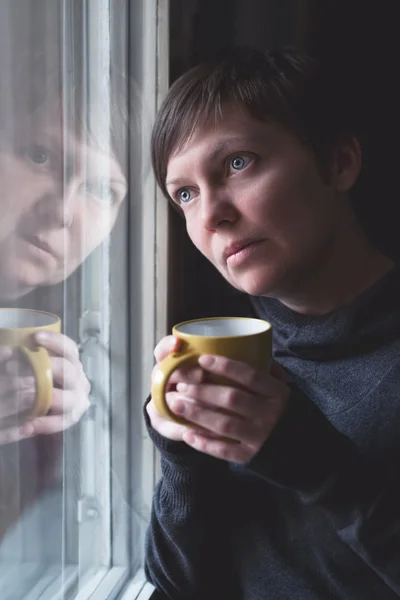 Smutný sama žena pít kávu v temné místnosti — Stock fotografie