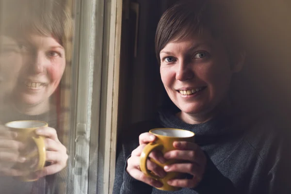 Vacker kvinna dricker kaffe i mörkt rum — Stockfoto