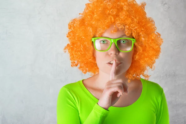 Oranje meisje met de vinger op de lippen — Stockfoto