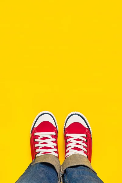 Voeten above, tiener in Sneakers permanent op gele achtergrond — Stockfoto