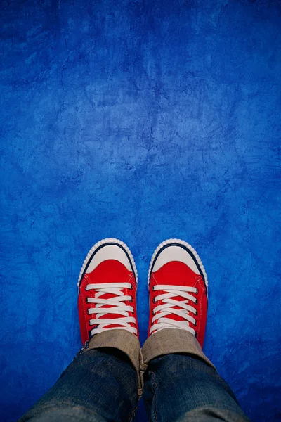 Pies desde arriba, adolescente en zapatillas de pie sobre fondo azul —  Fotos de Stock