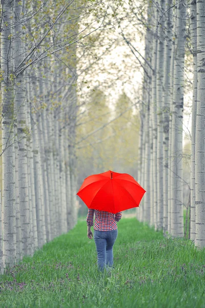 Mujer con paraguas rojo caminando lejos — Foto de Stock