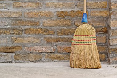 Household Broom For Floor Cleaning Leaning on Brick Wall clipart